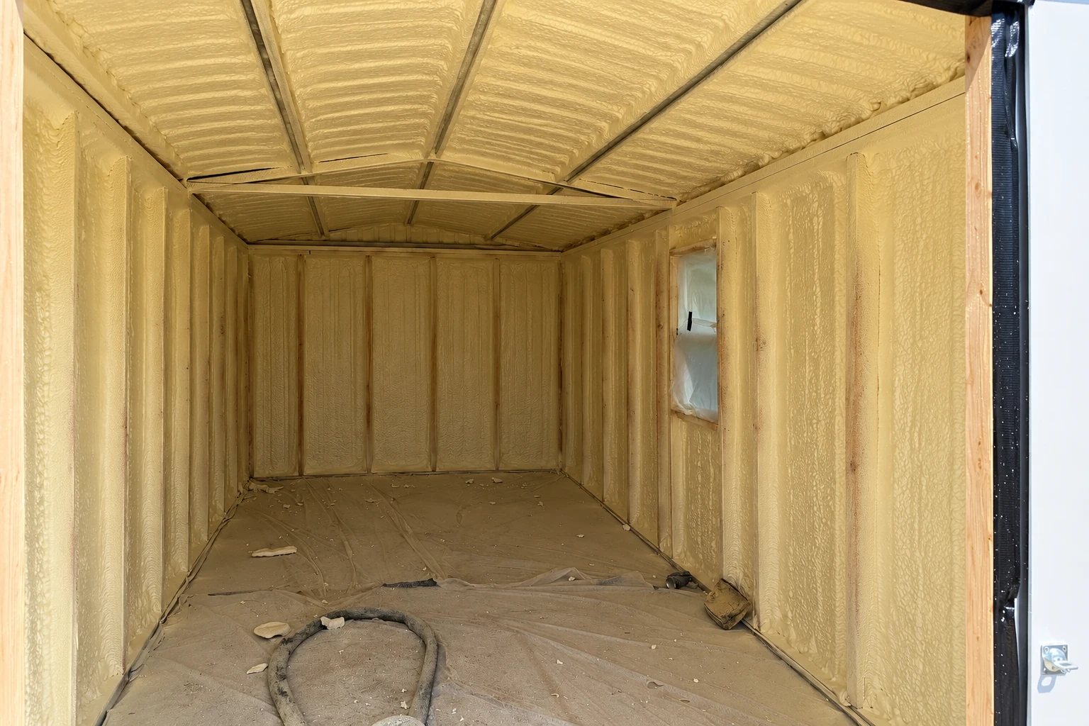 Small framed enclosure coated on its walls and ceiling with yellow closed-cell spray foam.